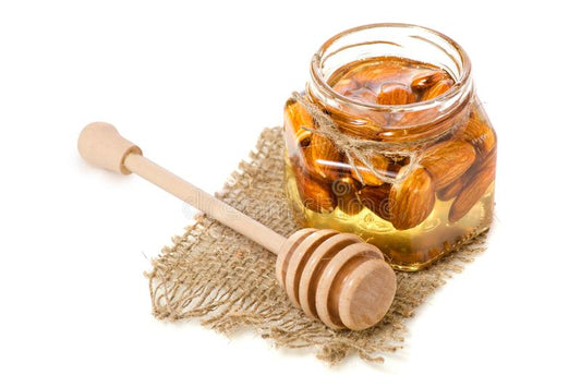 un-barattolo-del-miele-con-cucchiaio-per-le-mandorle-dei-dadi-106554251